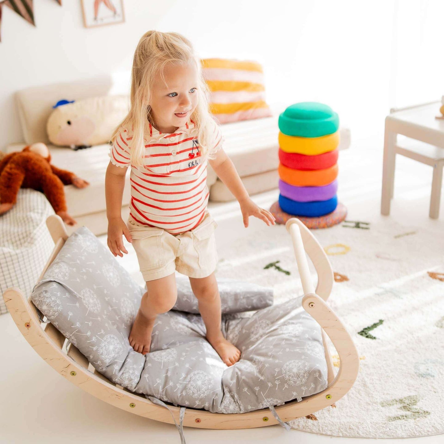 Kind spielt auf der Kletterwippe mit weichen Kissen in einem hellen Kinderzimmer