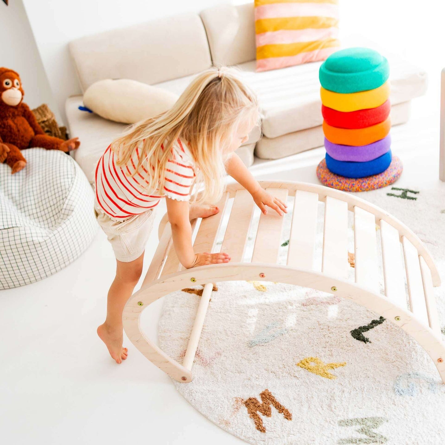 Ein Mädchen spielt mit dem Kletterbogen des Klettersets Äffchen in einem bunten und fröhlichen Spielzimmer.
