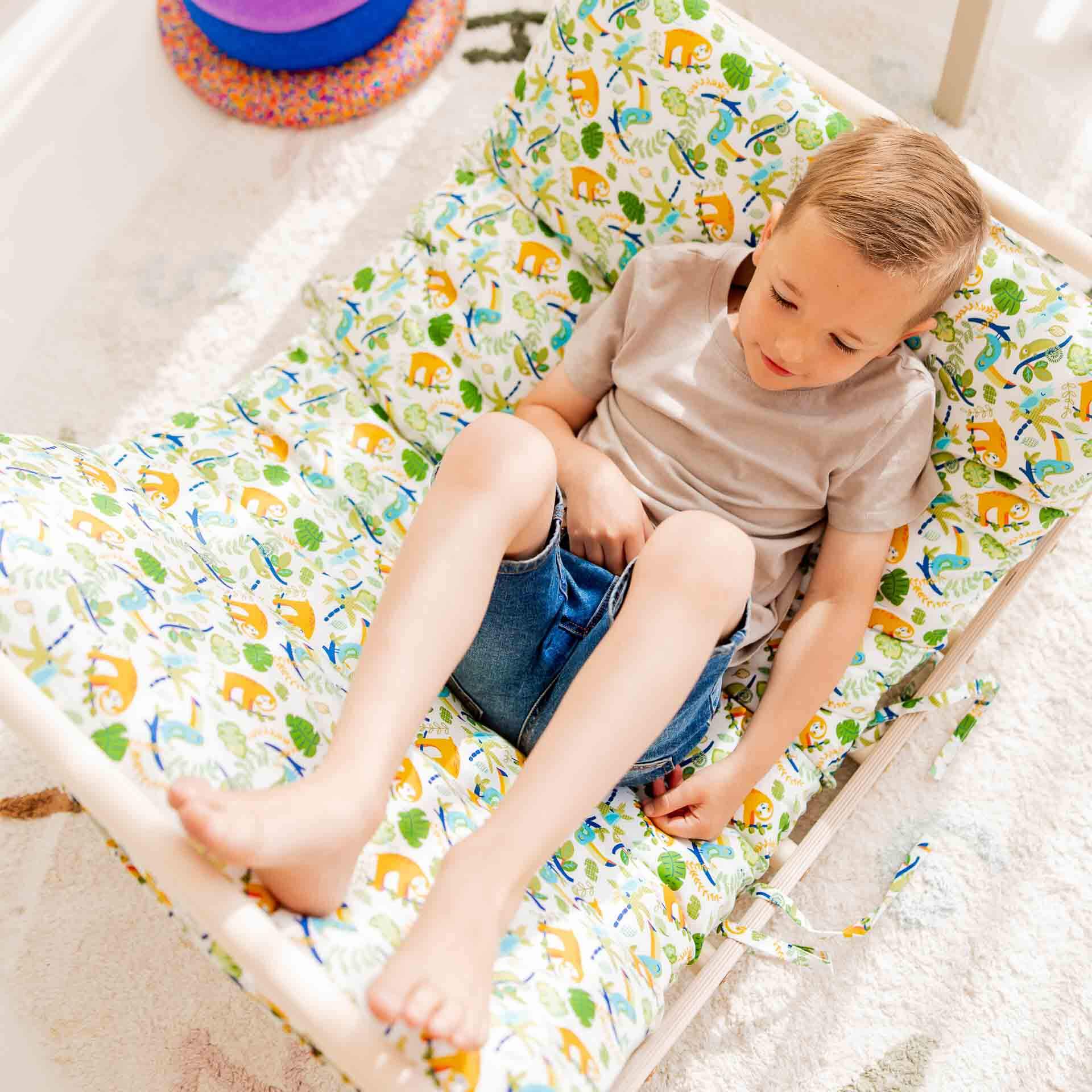 Glückliches Kind sitzt auf einem bunten Kletterbogen mit tierischem Muster, ideal für Spielerlebnis und Komfort.
