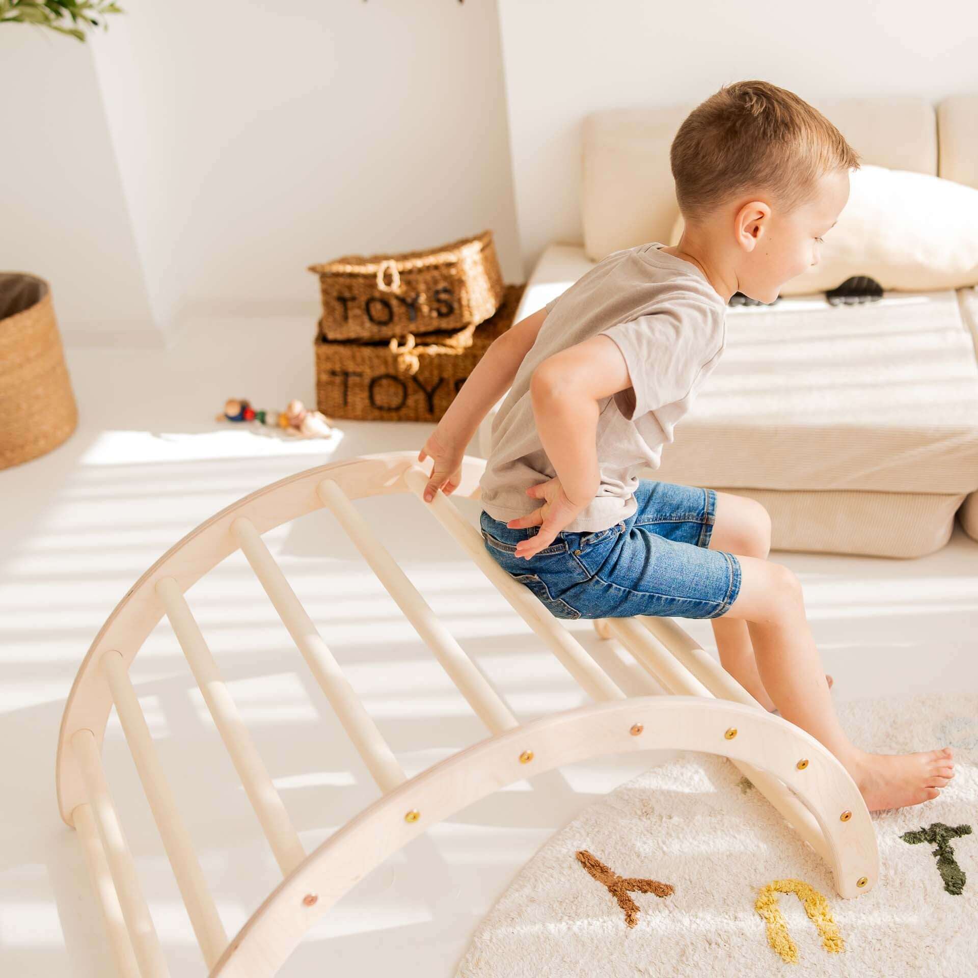 Ein Junge spielt auf einem Kletterbogen aus Holz, der Beweglichkeit und Freude fördert.