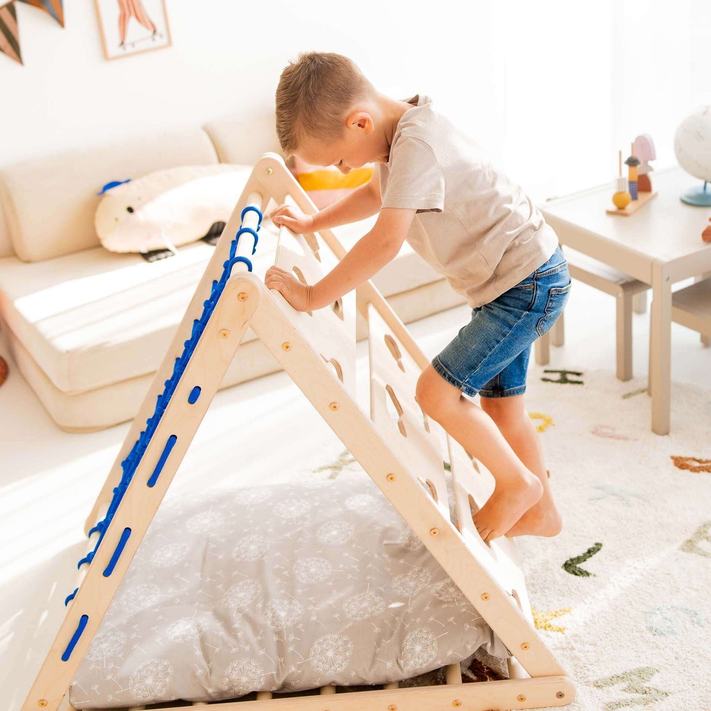 Kind klettert auf Kletterdreieck Äffchen aus Holz in einem hellen Kinderzimmer, fördert Bewegungsfähigkeiten.