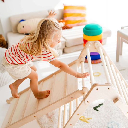 Kleines Kind, das spielerisch auf einem Rutschbrett / Hühnerleiter klettert, ideal für Abenteuertage.