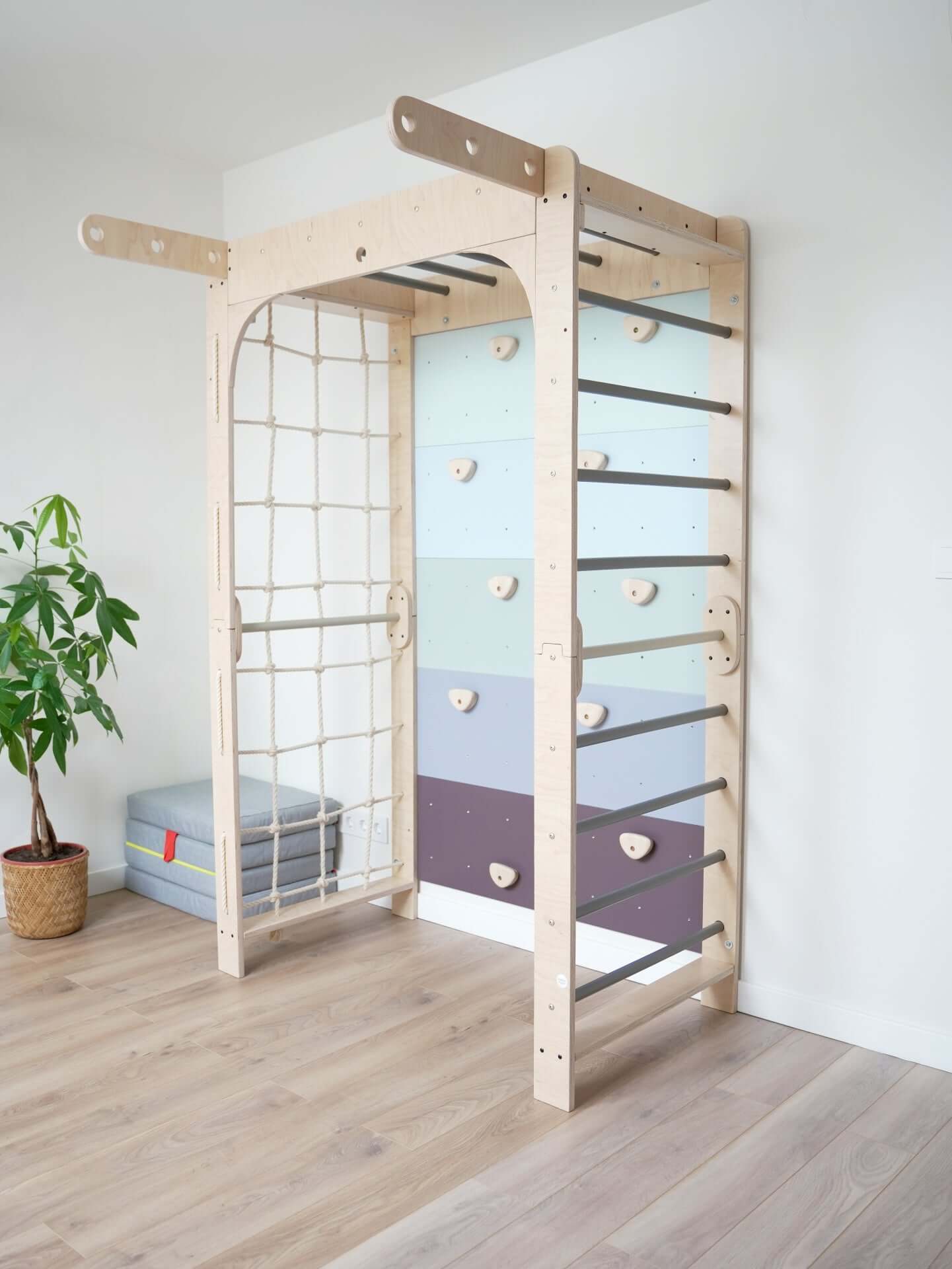 Indoor Spielplatz Kletterwand Klimby "Entdecker" für Kinder mit bunten Griffen und Kletterseil.