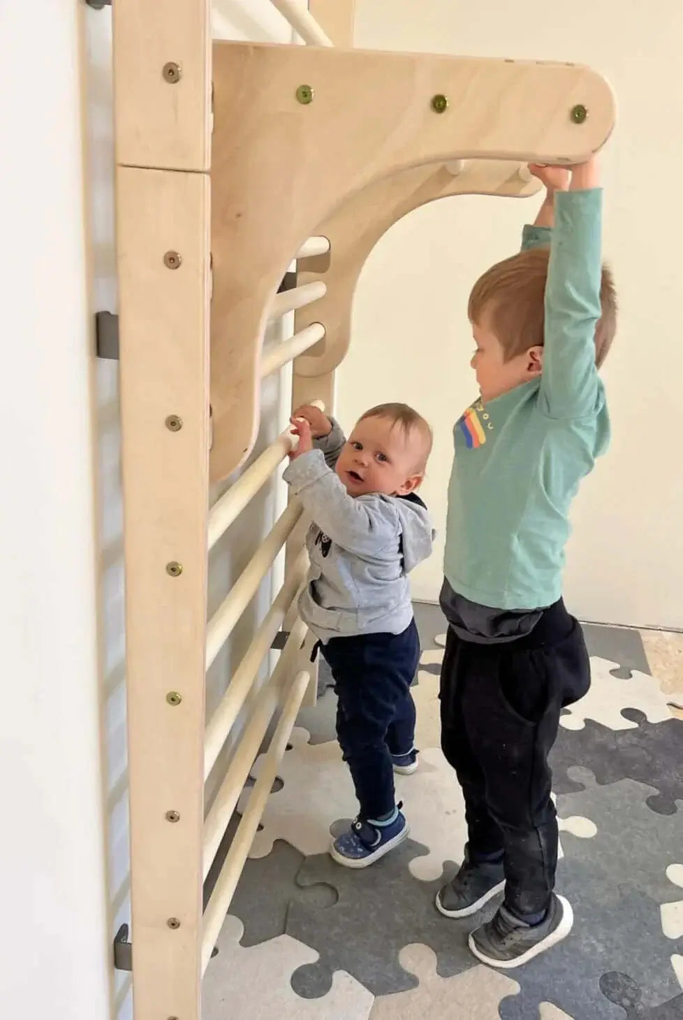 Zwei Kinder spielen an einer Kletterwand aus Holz, perfect for die Entwicklung ihrer Kletterfähigkeiten und Beweglichkeit.