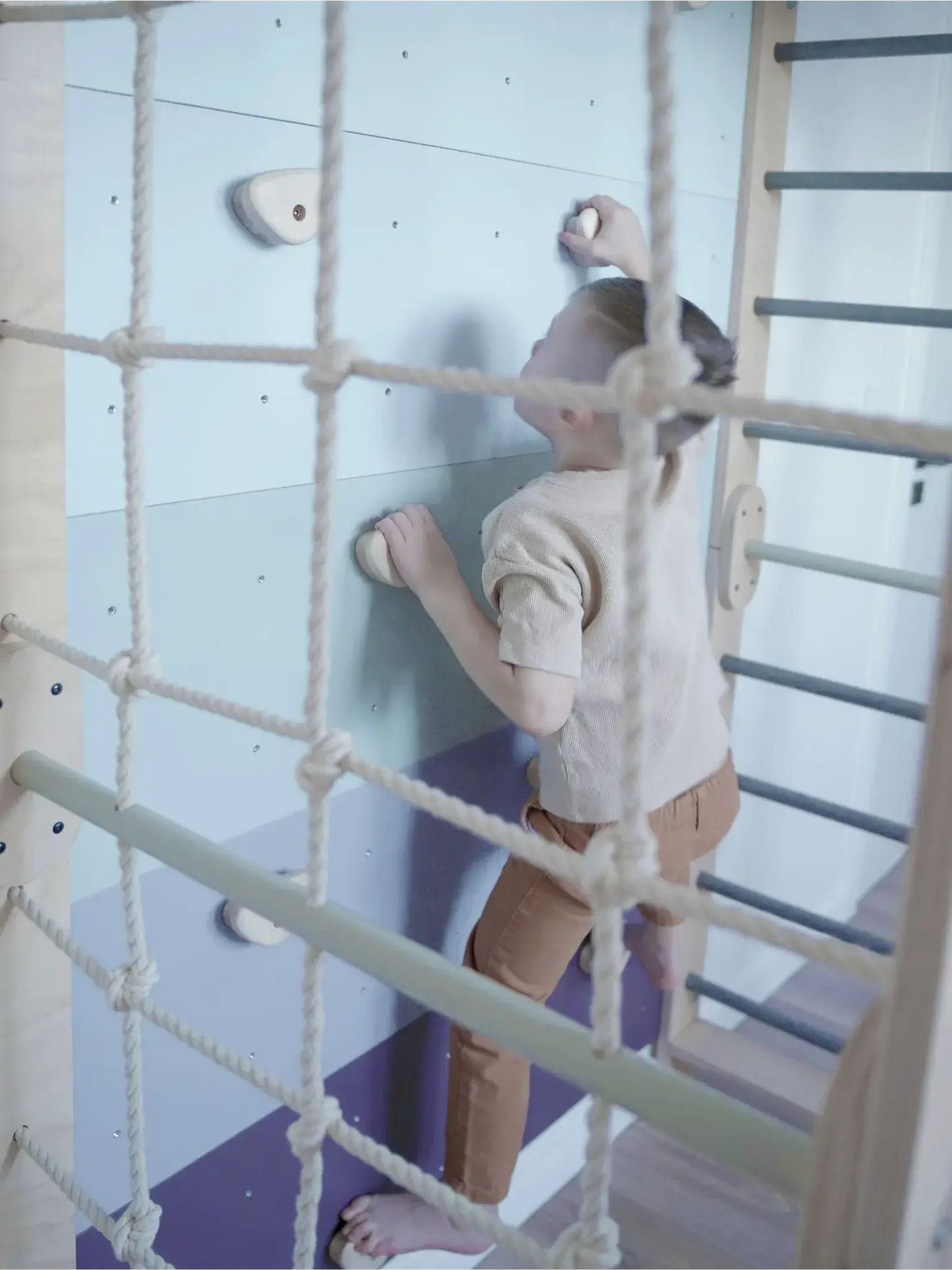 Ein Kind erklimmt die Kletterwand Klimby "Kletterkönig" im Spielzimmer, ideal für einen Indoor Spielplatz und Abenteuer.